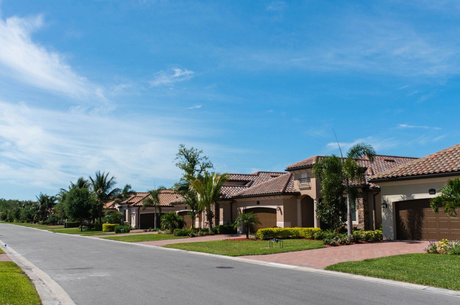 Single-story homes with barrel tile roofs and palms on a South Florida street