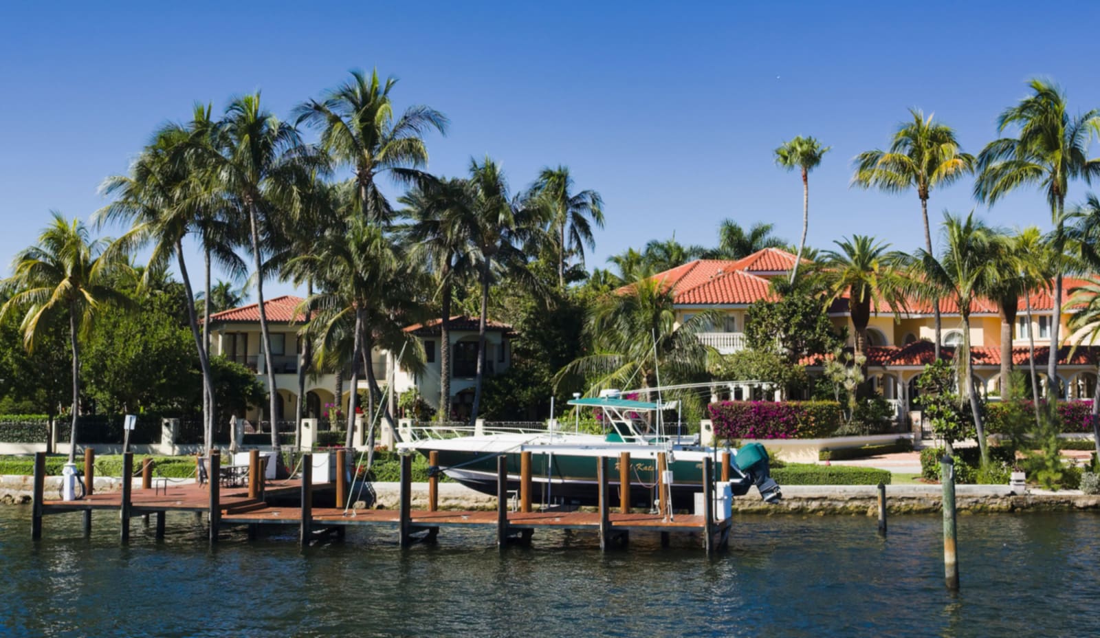Fort Lauderdale Intracoastal waterfront: a private dock and seawall with palms and Mediterranean-revival waterfront houses behind