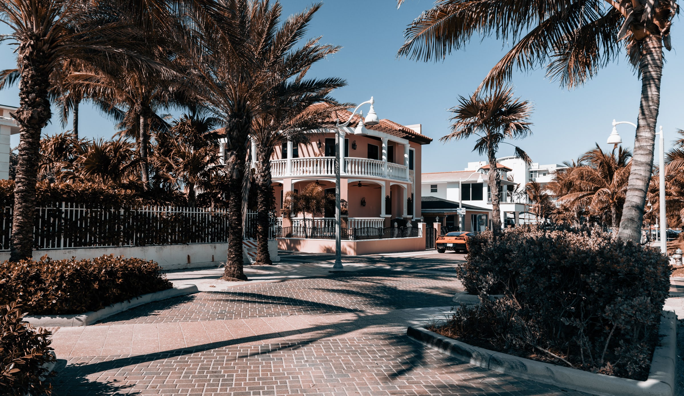 Palm-lined residential street in Hollywood, Florida, with a two-story home behind a low wall